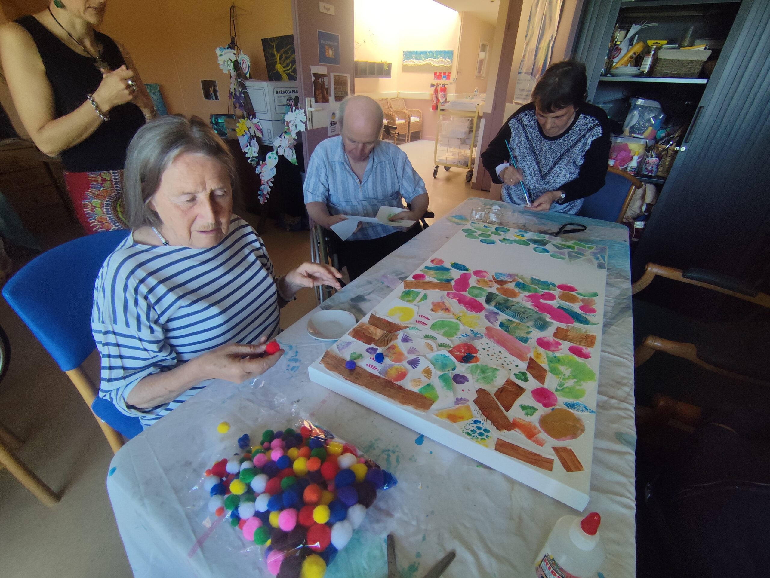 Mal-voyants et personnes agées découpant des morceaux d'oeuvres pour faire une mosaïque